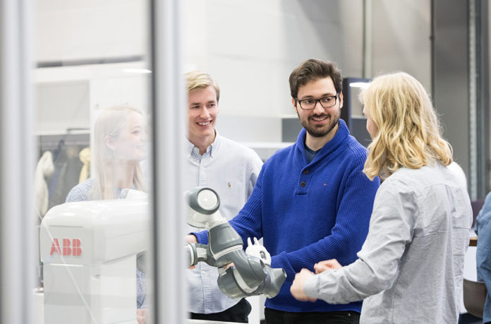 Auszubildende an einem Roboter.