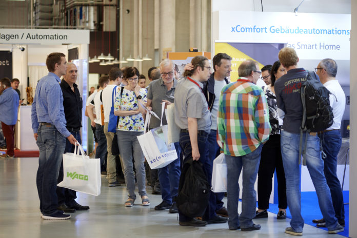 Eine Personenmenge steht an einer Ausstellung vor Ständen.