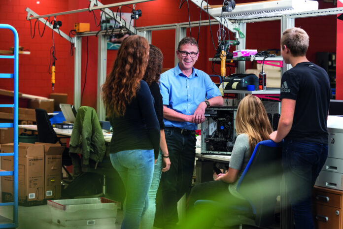 Lehrlinge mit einem Lehrmeister am Arbeitsplatz.